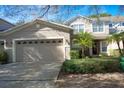 Tan two-story townhome with two-car garage and mature palm trees at 980 Crestwood Commons Ave, Ocoee, FL 34761