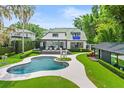 Beautiful backyard features an in-ground pool, lounge chairs, and guest house surrounded by green lawns at 1336 College Pt, Winter Park, FL 32789