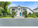 Charming white home showcasing a whimsical blue sky door and manicured front yard at 1336 College Pt, Winter Park, FL 32789