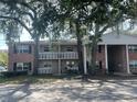 Charming condo building featuring brick accents, white railings, and large trees adding to the curb appeal at 2500 Lee Rd # 202, Winter Park, FL 32789