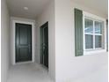 Covered entryway featuring a side door, front door with white trim, and a green window shutter at 953 Waterfall Blvd, Davenport, FL 33837