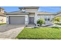 Front exterior with lush green landscaping, well-manicured lawn, and a gray stone exterior and matching garage at 247 Hampton Loop, Davenport, FL 33837