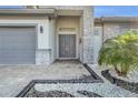 Front exterior with lush green landscaping, well-manicured lawn, and a gray stone exterior and matching garage at 247 Hampton Loop, Davenport, FL 33837