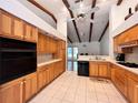 Bright kitchen features wooden cabinets, a black oven, and tile floors beneath a vaulted ceiling with beams at 2047 Friar Tuck Ln, Orange City, FL 32763