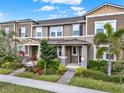 Charming townhouse exterior featuring lush landscaping, a covered entryway, and multiple windows at 16521 Prairie School Dr, Winter Garden, FL 34787