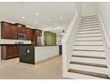 Modern kitchen features dark wood cabinets, stainless steel appliances, a large island, and staircase at 16521 Prairie School Dr, Winter Garden, FL 34787