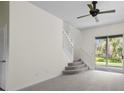 Bright living room with neutral carpet, ceiling fan, stairs, and sliding glass doors leading to the backyard at 293 Saxony Ct, Winter Springs, FL 32708
