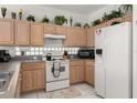 Kitchen with wood cabinets, white appliances, and tile floors at 2983 Sunset Vista Blvd, Kissimmee, FL 34747