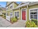 Charming townhome entrance featuring a vibrant red door, complemented by manicured landscaping and a white picket fence at 4004 Santa Maria Dr # 105, Kissimmee, FL 34741