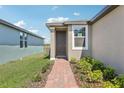 Inviting front entrance with a well-manicured garden, brick pathway and contemporary door at 4031 Cooperleaf Ln, Poinciana, FL 34759