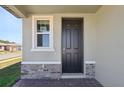 A close-up of the front door with a small window to the side, surrounded by stone and brick accents at 4034 Copperleaf Ln, Poinciana, FL 34759