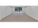 Living room with carpet and glass sliding doors that open to an outdoor patio area with green shrubs and trees at 530 E Central Blvd # 102, Orlando, FL 32801