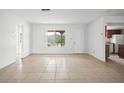 Open living area with tile flooring, white walls, a large window, and an adjacent kitchen area at 10305 Licorice Way, Orlando, FL 32821