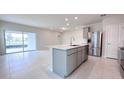 Modern kitchen features an island, stainless steel appliances, and sliding glass doors to the backyard at 2206 Lovely Ln, Davenport, FL 33897