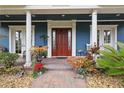 Inviting front porch with red front door and decorative potted plants at 2438 River Rise Ct, Orlando, FL 32828