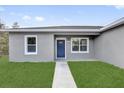 Close up view of a home's entry featuring a blue front door, windows, walkway, and manicured lawn at 42 Fisher Way Trak, Ocklawaha, FL 32179