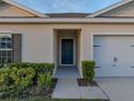 Entrance view of the home's front door, complemented by lush greenery and a two-car garage at 1207 Tank Trl, Haines City, FL 33844