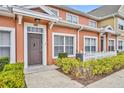 Exterior shot of a townhouse with a brown door and white picket fence at 2200 San Vittorino Cir # 104, Kissimmee, FL 34741