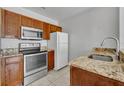 Kitchen featuring stainless steel appliances, granite countertops, and wooden cabinets at 2200 San Vittorino Cir # 104, Kissimmee, FL 34741