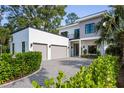 Modern home showcases a two-car garage, gravel driveway, and lush, green landscaping at 2412 Chantilly Ave, Winter Park, FL 32789