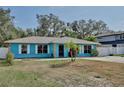 Inviting single-story home featuring a light blue exterior, metal roof, and a well-manicured lawn at 27622 Lois Dr, Tavares, FL 32778