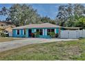 Charming ranch-style home with vibrant blue exterior, metal roof, stone accents, and large driveway at 27622 Lois Dr, Tavares, FL 32778