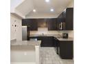 Well-lit kitchen featuring dark cabinets, granite countertops, stainless steel appliances, and tiled flooring at 1820 Shumard Ave, St Cloud, FL 34771