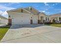 Beige one-story home featuring a two-car garage, well-manicured lawn, and stone accents at 1942 Rankin St, Kissimmee, FL 34744