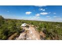 Aerial view of a secluded home surrounded by lush trees and featuring a long dirt driveway and a detached garage at 40200 Swift Rd, Eustis, FL 32736