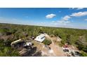 Overhead view of a unique home with a metal roof nestled among trees, along with numerous vehicles and outdoor equipment at 40200 Swift Rd, Eustis, FL 32736