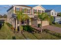 Two-story home featuring tan siding, red shutters, a brick driveway and an attached two-car garage at 613 Bloom Ter, Davenport, FL 33837