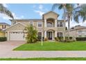 Two-story home showcasing manicured lawn and lush tropical landscaping, complemented by a two car garage at 10068 Chardonnay Dr, Orlando, FL 32832