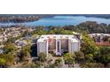 Aerial view of condo building with balconies, surrounded by mature trees and close to a lake at 1150 Carmel Cir # 503, Casselberry, FL 32707