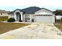 Charming single-story home showcasing the garage, driveway, and manicured front lawn at 11501 Pineloch Loop, Clermont, FL 34711