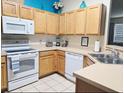 Well-lit kitchen featuring light wood cabinets, white appliances, and decoratively accented with pops of color at 1217 Cypress Pointe Blvd, Davenport, FL 33896