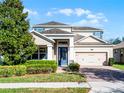 Inviting two-story home with blue accents, a brick driveway, and a well-maintained front yard at 15863 Citrus Grove Loop, Winter Garden, FL 34787