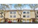 Charming yellow two-story townhome with a tile roof, white trim, garages, and manicured landscaping at 1616 Legacy Park Dr # 1616, Maitland, FL 32751
