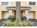 Close up exterior image of a tan building with garages and a large tree at 1616 Legacy Park Dr # 1616, Maitland, FL 32751