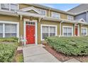 Stylish townhome showcasing a striking red front door and neatly trimmed hedges, creating a welcoming entrance at 2611 Gala N Rd # 105, Kissimmee, FL 34746