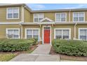 Attractive townhouse featuring a bold red door framed by manicured bushes and well-maintained surroundings at 2611 Gala N Rd # 105, Kissimmee, FL 34746