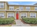 Inviting townhouse with a vibrant red front door, complemented by tidy landscaping and a small outdoor seating area at 2611 Gala N Rd # 105, Kissimmee, FL 34746