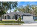 Charming single-story home with blue siding, manicured lawn, and an attached two-car garage at 2810 Abbey Ave, Orlando, FL 32833