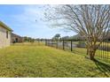 A green backyard featuring a black fence with a pond view at 4976 Creekside Park Ave, Orlando, FL 32811