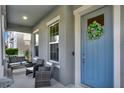 Inviting front porch with seating area and a stylish blue door adorned with a wreath at 10319 Austrina Oak Loop, Winter Garden, FL 34787