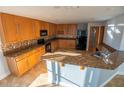 Well-equipped kitchen with granite countertops, wooden cabinets, black appliances, and tile backsplash at 1926 Binnacle St, Kissimmee, FL 34744