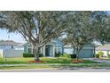 Inviting single-story home with well-manicured landscaping, mature trees, and light blue exterior at 38 Lakeview Reserve Blvd, Winter Garden, FL 34787