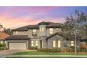 Elegant two-story home featuring a turret, stone accents, tile roof, and well-manicured landscaping at dusk at 5774 Fulham Pl, Sanford, FL 32771