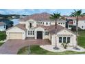 Gorgeous home showcasing a paver driveway, lush landscaping, and Mediterranean-style architecture at 1191 Terralago Way, Kissimmee, FL 34746