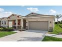 Inviting single-story home with a covered porch, stone accents, lush landscaping and a two-car garage at 1206 Normandy Dr, Haines City, FL 33844