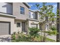 Townhouse exterior showcasing gray tones, a brick driveway, landscaping and an attached garage at 1213 S Station Pl # 404, Orlando, FL 32809